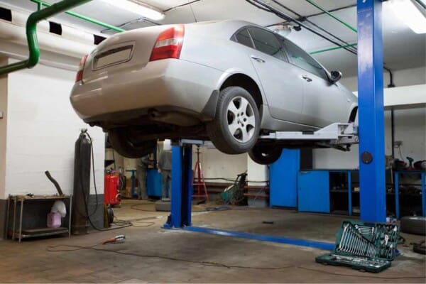 four-door-sedan-hoisted-up-in-repair-garage-for-inspection-picture-id158036150__ResizedImageWzYwMCw0MDBd