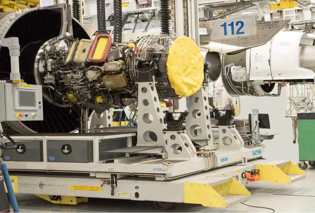 Aerospace engine on a mobile vertical assembly platform in a high-tech manufacturing space.