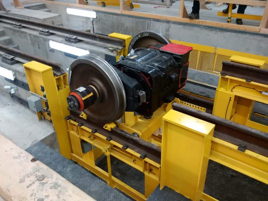 Wheelset on yellow maintenance stand in railcar servicing facility.