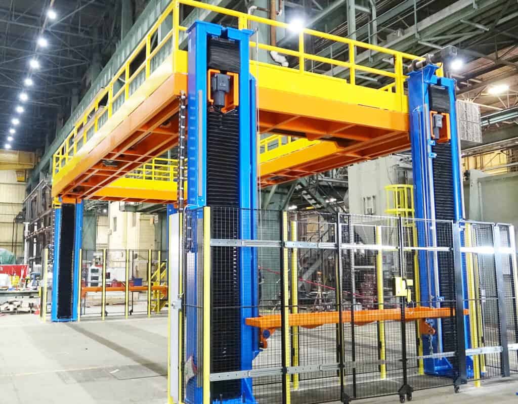 Tall custom work positioners with blue and yellow vertical platform lift in industrial hall.
