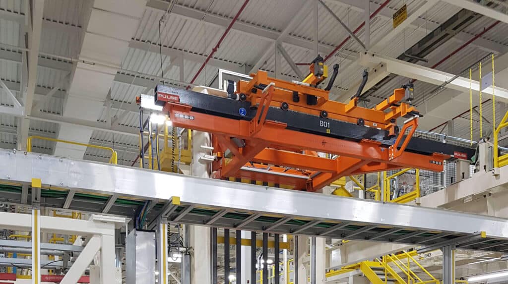 "Orange overhead custom work positioner with lifting attachments in a manufacturing plant.