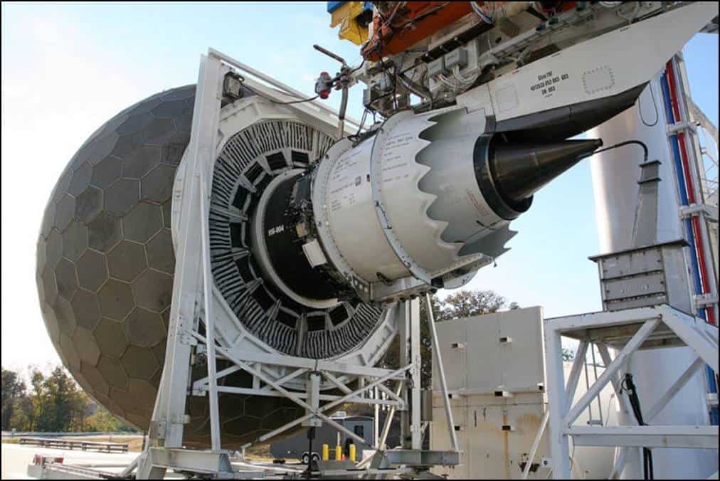 An aerospace engine mounted on a testing rig in an outdoor facility.