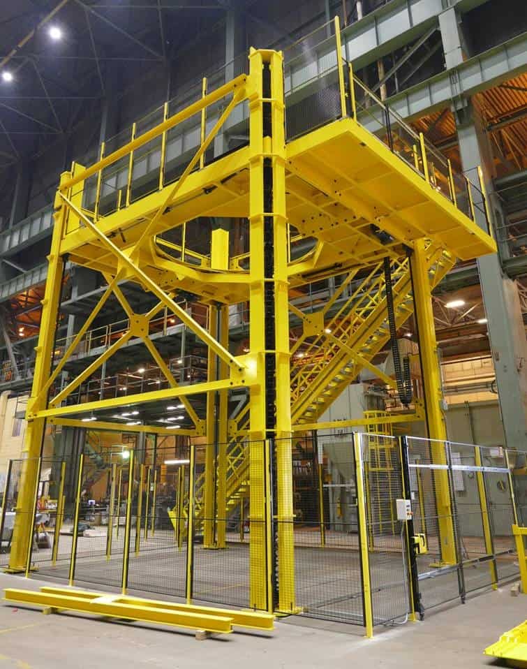 A large, yellow industrial structure with stairs and platforms for custom personnel lifts in a warehouse.