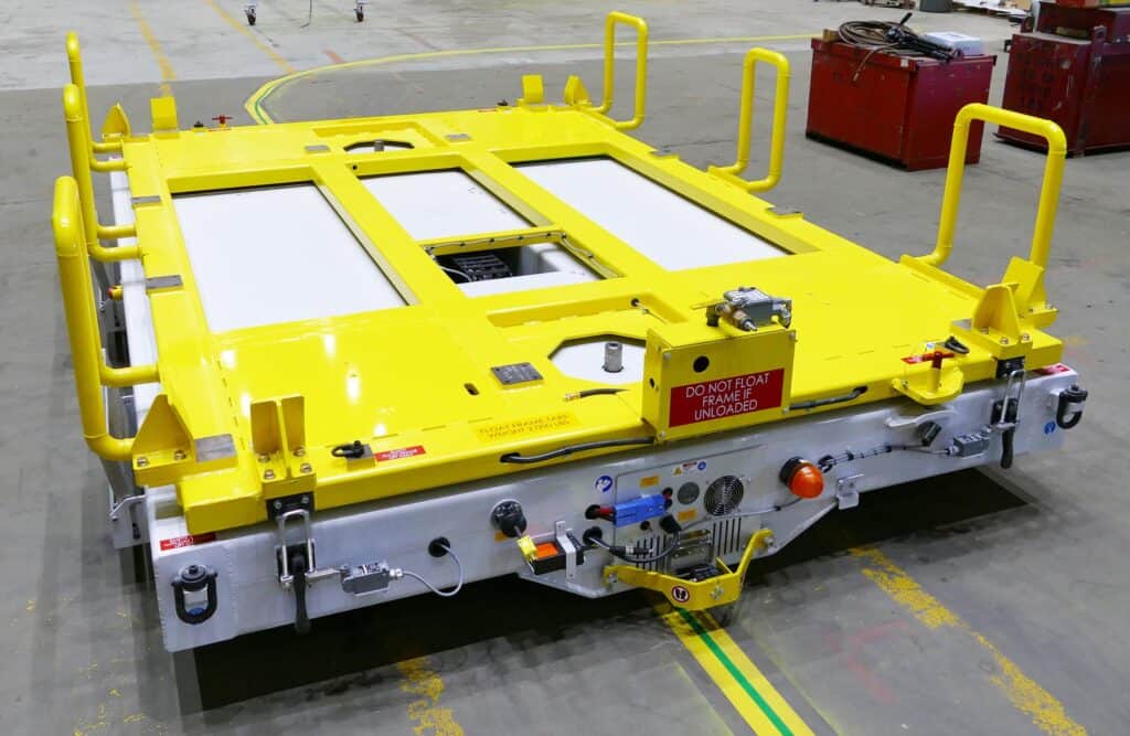 Yellow equipment frame used in aerospace material handling for transporting heavy machinery in an industrial facility.