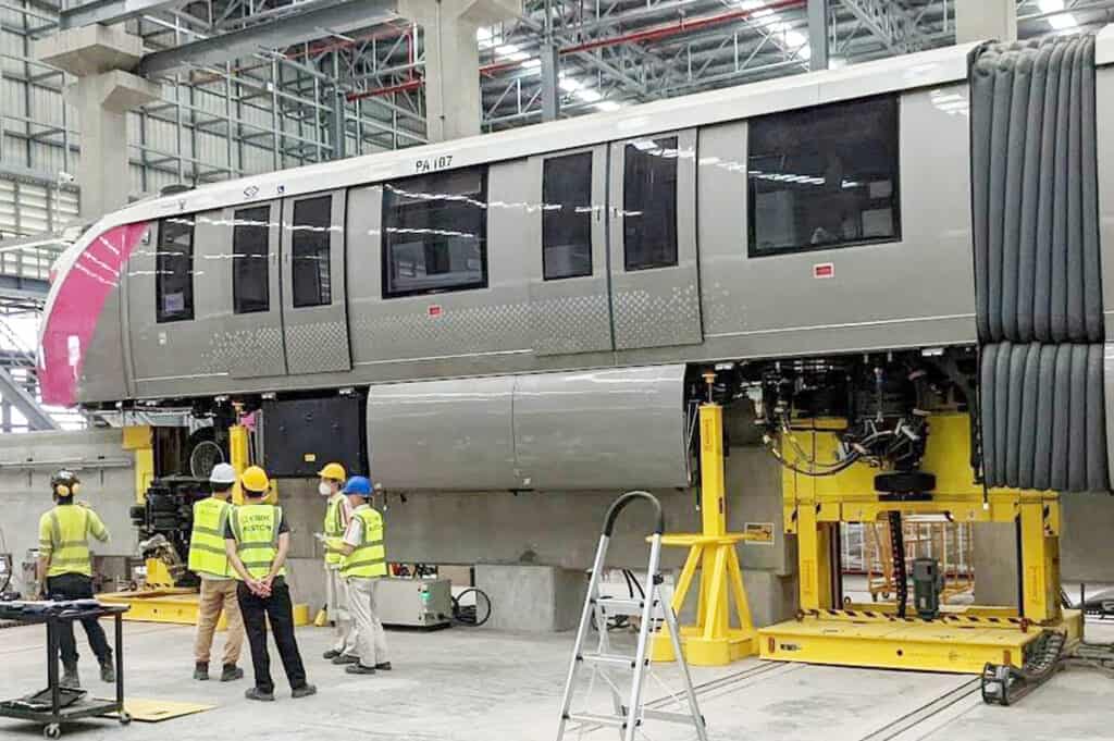 Workers servicing monorail bogie in maintenance facility.