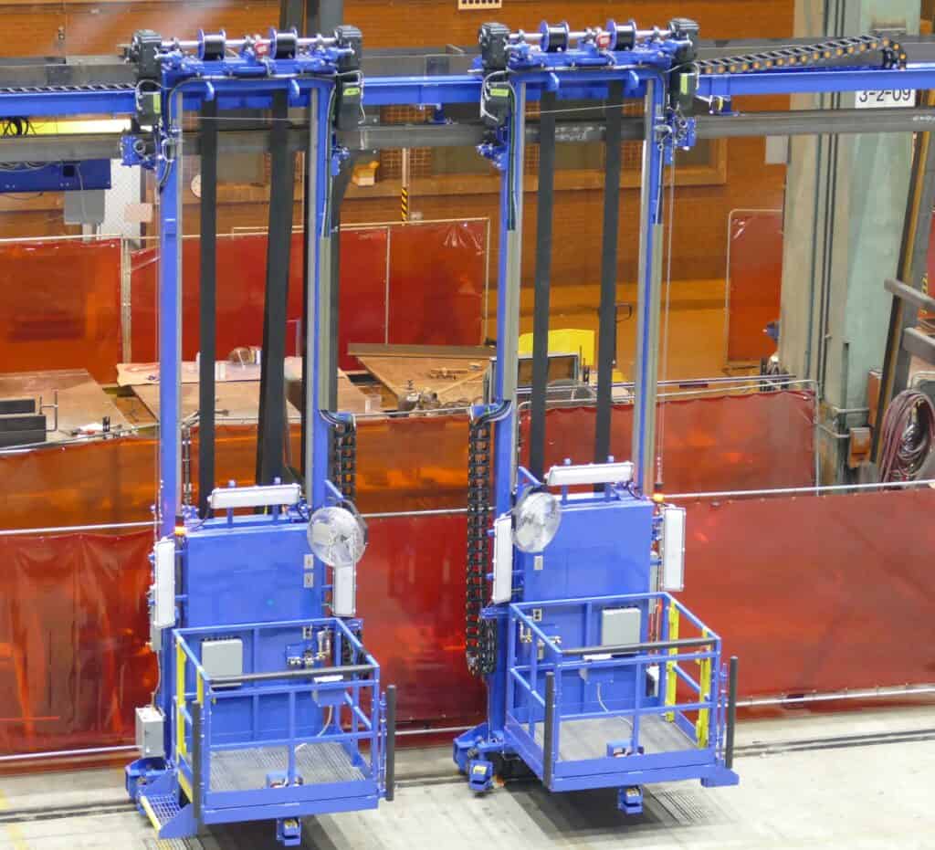 Two blue vertical lift platforms in an industrial facility designed for custom personnel lifts.